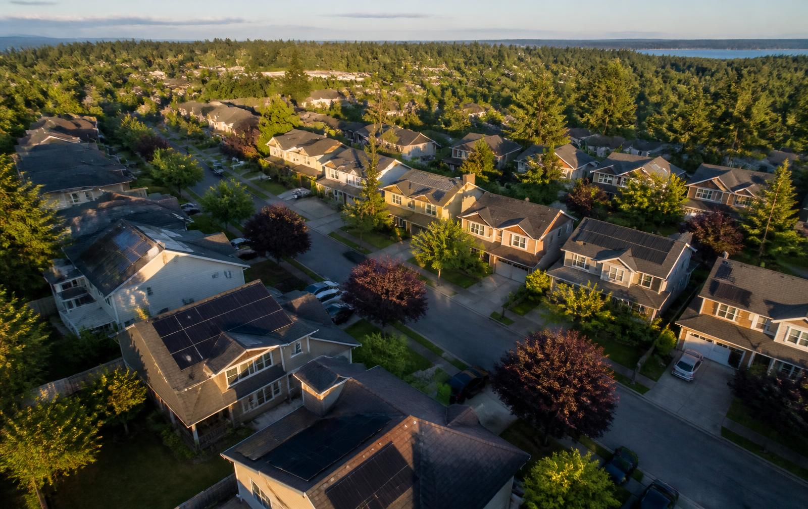 Drone view of a neighborhood with rooftop solar panels at golden hour