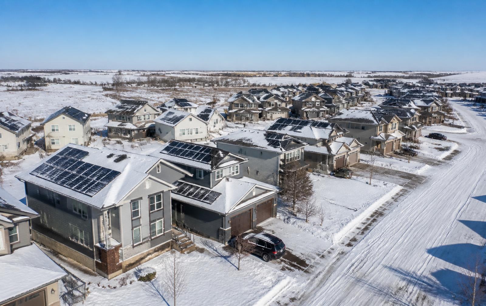 Aerial view of snow-covered Canadian homes with solar panels in winter